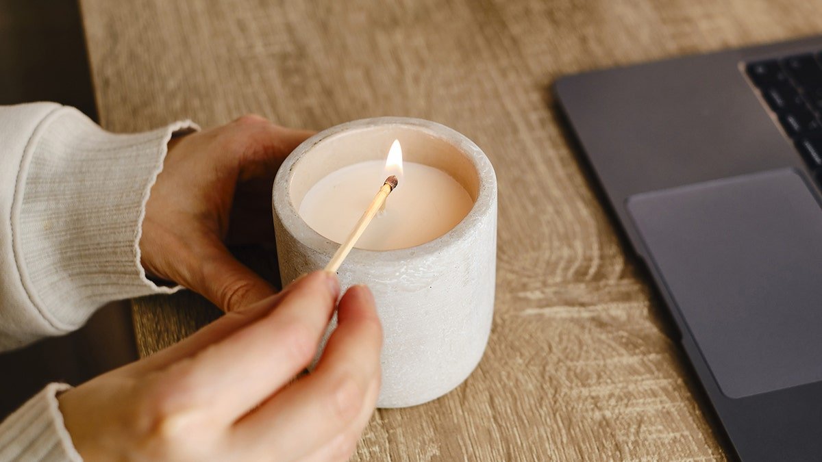 Girl lights candle at desk