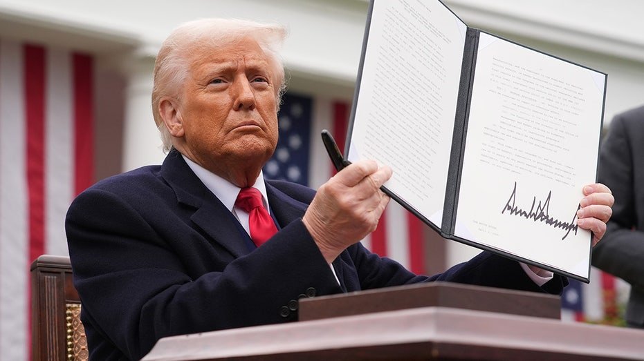 President Donald Trump holds up signed executive order