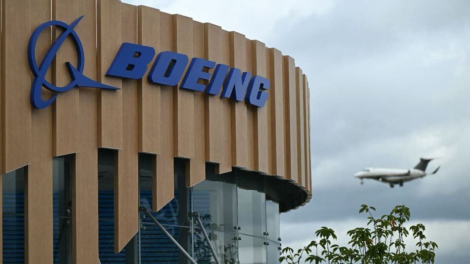 plane flies by Boeing building