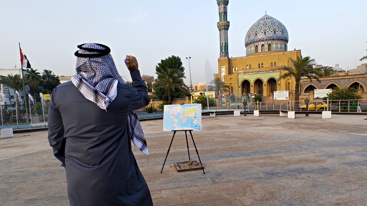 Sorin Mihailovici throwing a dart in Iraq. A man has travelled to over 60 countries by throwing a dart a world map and visiting where ever it lands.