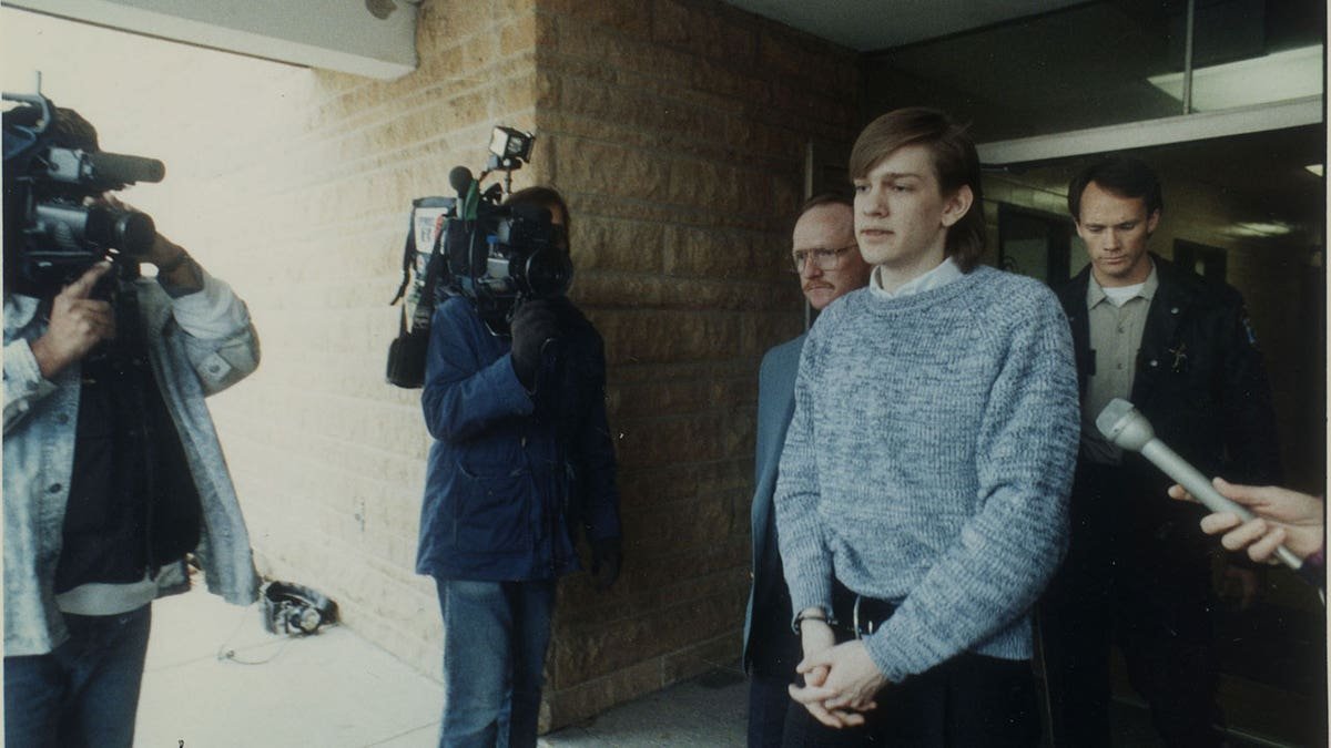 David Brom was escorted to a car in handcuffs