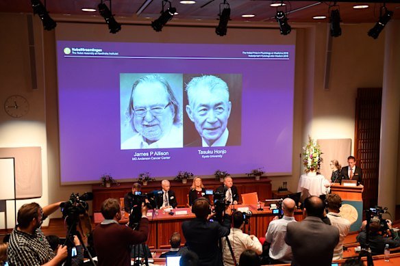 James Allison and Tasuku Honjo are shown on the screen during the Nobel Prize in Medicine presentation in Stockholm in 2018.