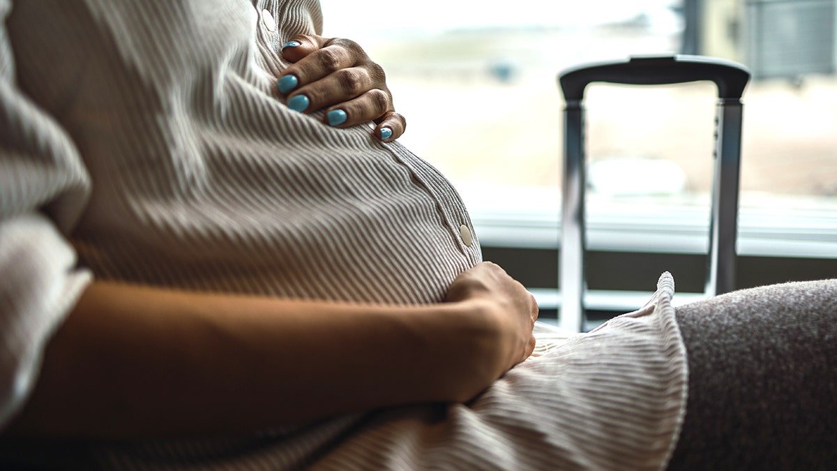 pregnant flight passenger at airport with luggage