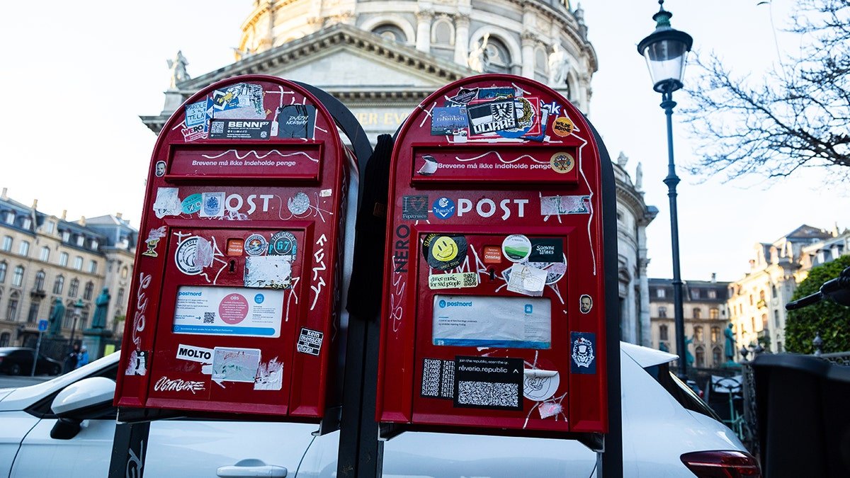Two red mailboxes are shown in front of a church in Copenhagen, Denmark.