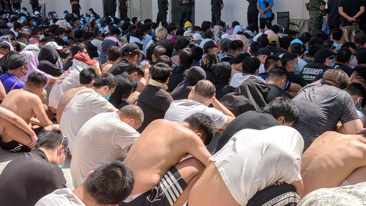 People sit inside a compound where foreign workers are being held after a police crackdown.