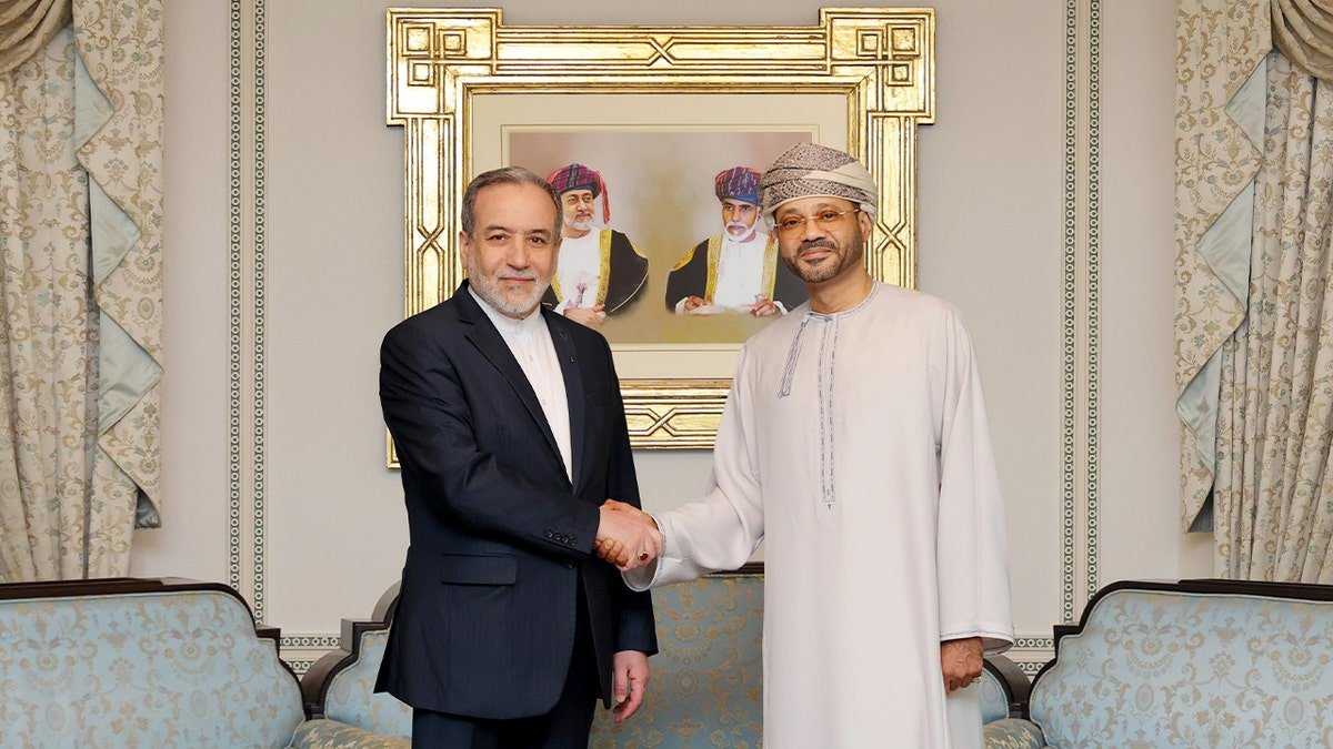 Two Middle Eastern diplomats shake hands during a formal meeting.
