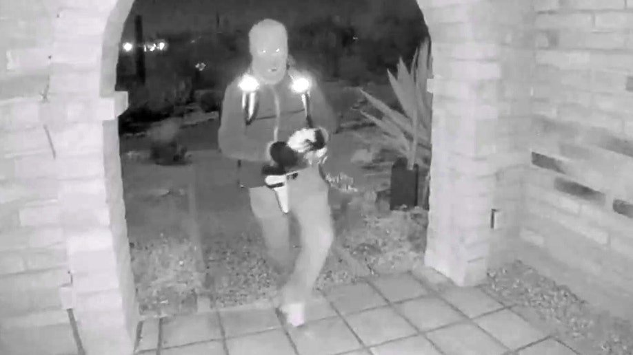 A view from a doorbell camera showing an armed individual outside the residence of Nancy Guthrie in Tucson, Arizona