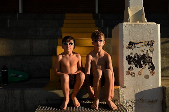 Brothers Maddox Chapman (aged eight, left) and Beckham Chapman (aged nine, right) sit in the stands at the Dubbo Aquatic Leisure Centre before having a swim in the early morning before school.