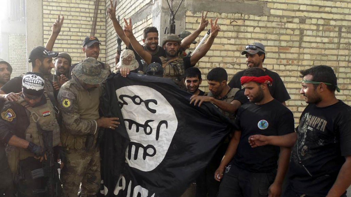 Iraqi security forces pose with ISIS flag which they pulled from University of Anbar on July 26, 2015. Forces clashed with ISIS militants inside the compound.