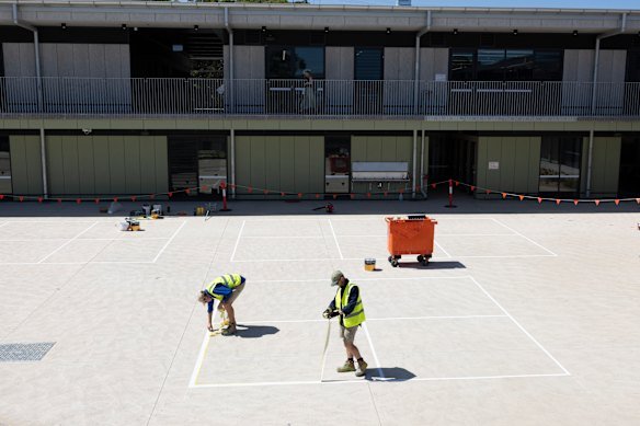 Workers painting lines for the school’s handball courts on Thursday.