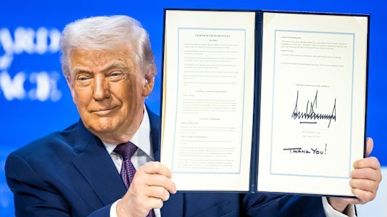 US President Donald Trump holds up a signed Board of Peace charter.
