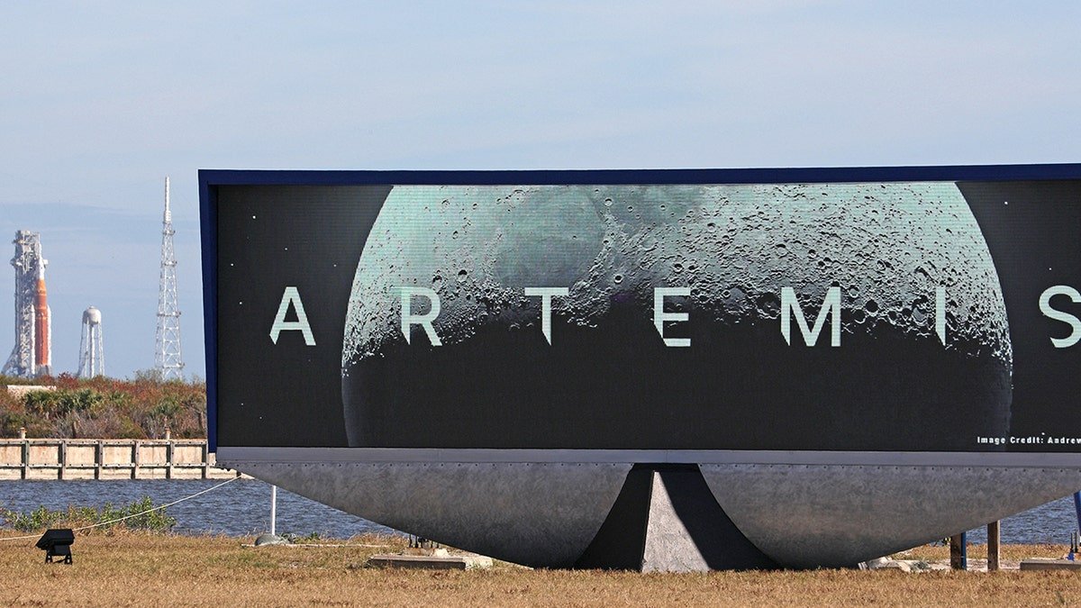 Artemis sing in front of rocket at Kennedy Space Center