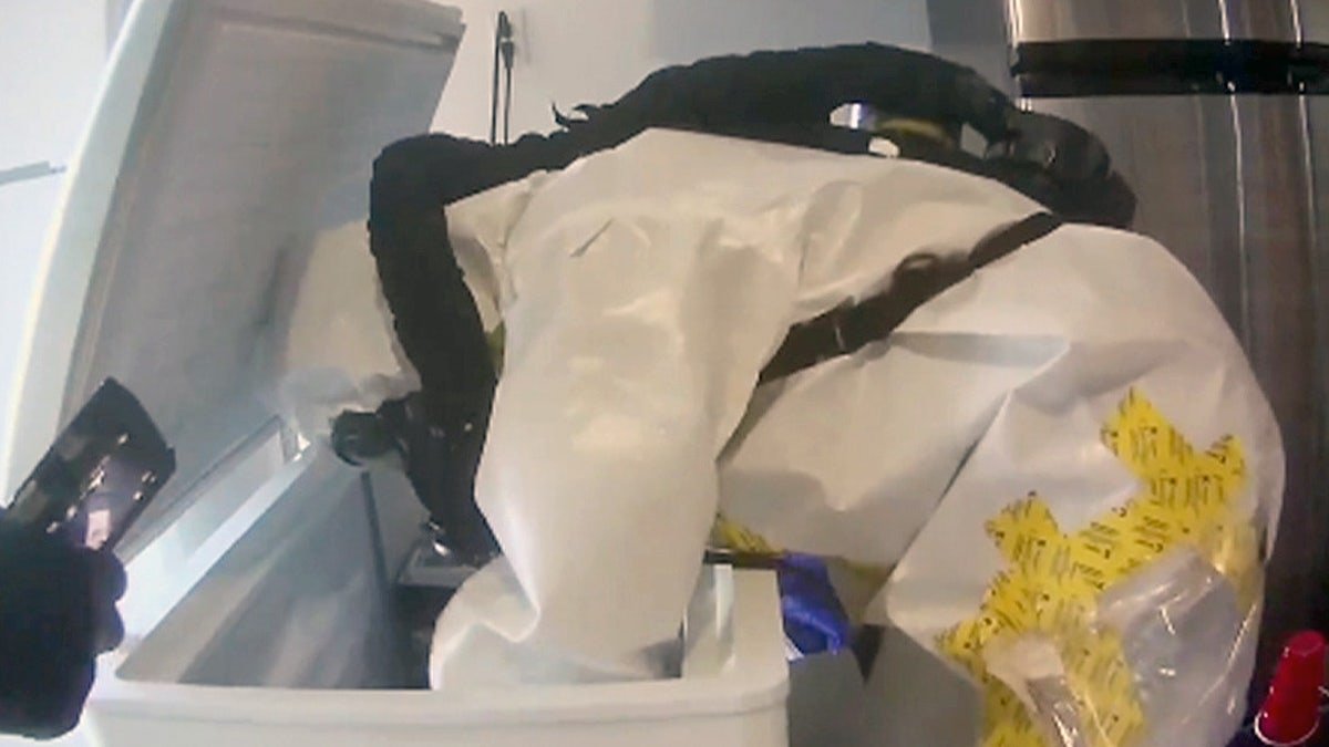 A worker in a hazmat suit searches through material found at the Las Vegas house.