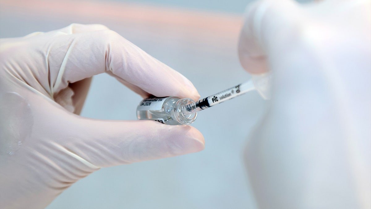 A doctor draws botox with an injection syringe