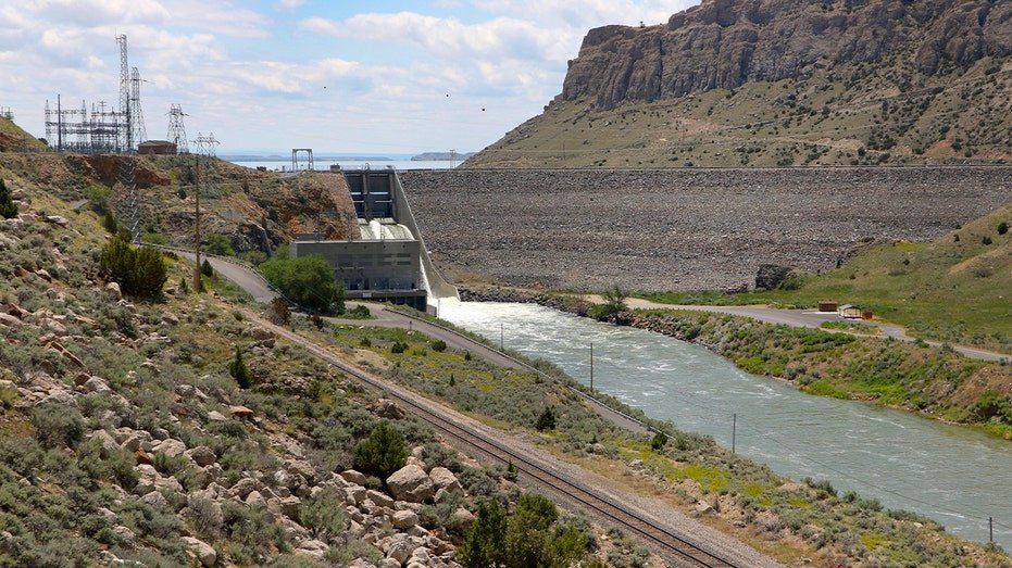 An earth-fill dam spans a wide river valley in central Wyoming, holding back a large reservoir.
