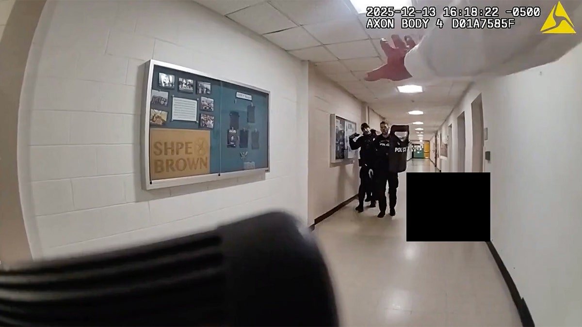 Officers walking down the hall with a shield.
