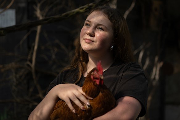 Mimi Highgate, 14, who takes part in the Hands on Learning program at Mount Eliza Secondary College, in the aviary with one of the chooks.