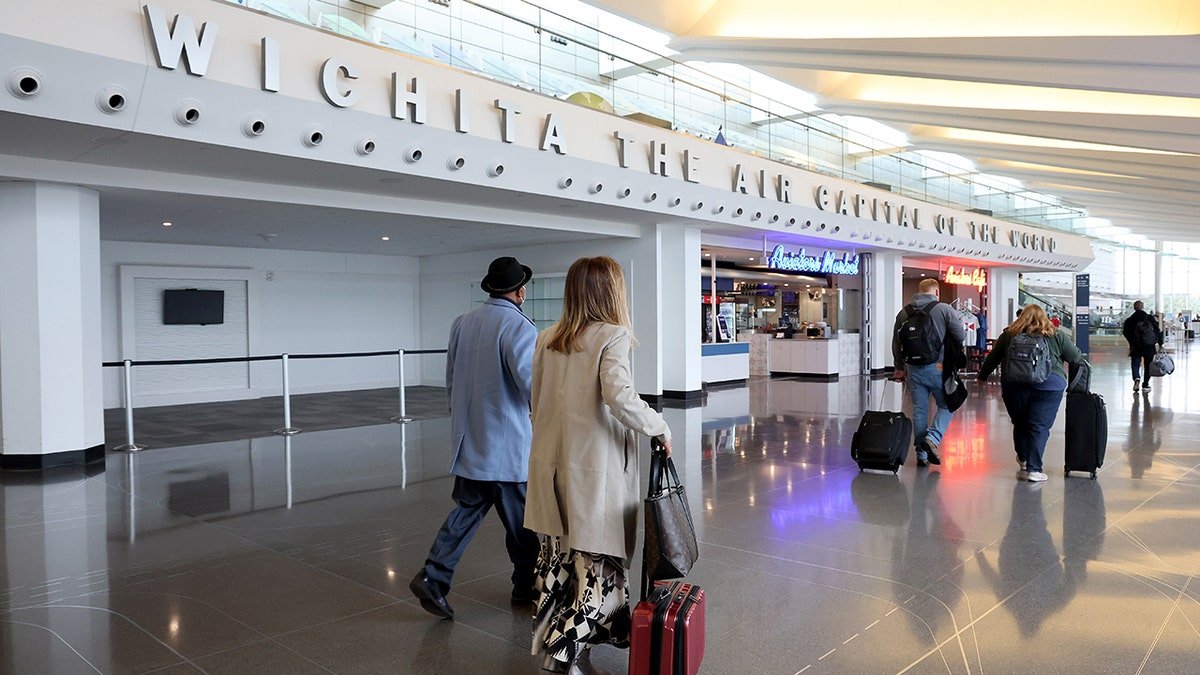 Travelers walk through the Dwight D. Eisenhower National Airport with suitcases and luggage on January 30, 2025 in Wichita, Kansas.