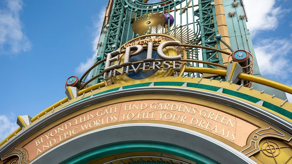 Visitors walk beneath a grand themed gateway during a preview event at a new Orlando amusement park.