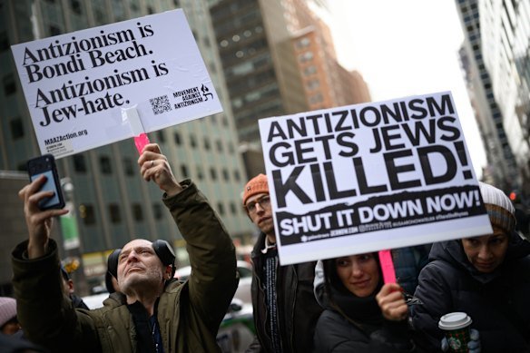 People hold signs at a vigil outside the Australian consulate in New York City after the Bondi massacre.