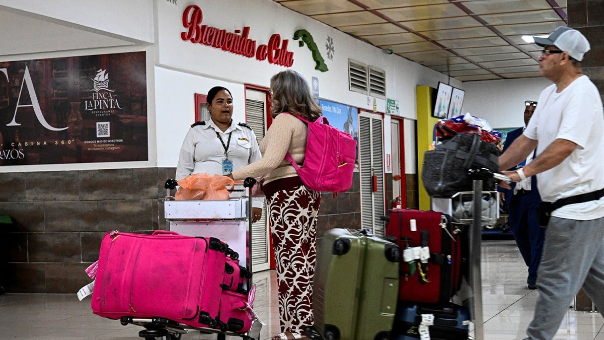 Travelers walk through a Havana airport terminal pulling rolling suitcases.