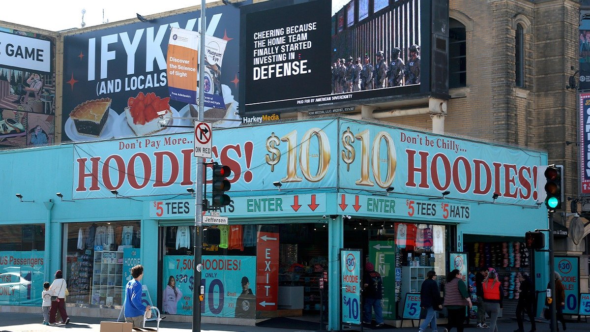 billboard says "cheering because the home team finally started investing in defense."