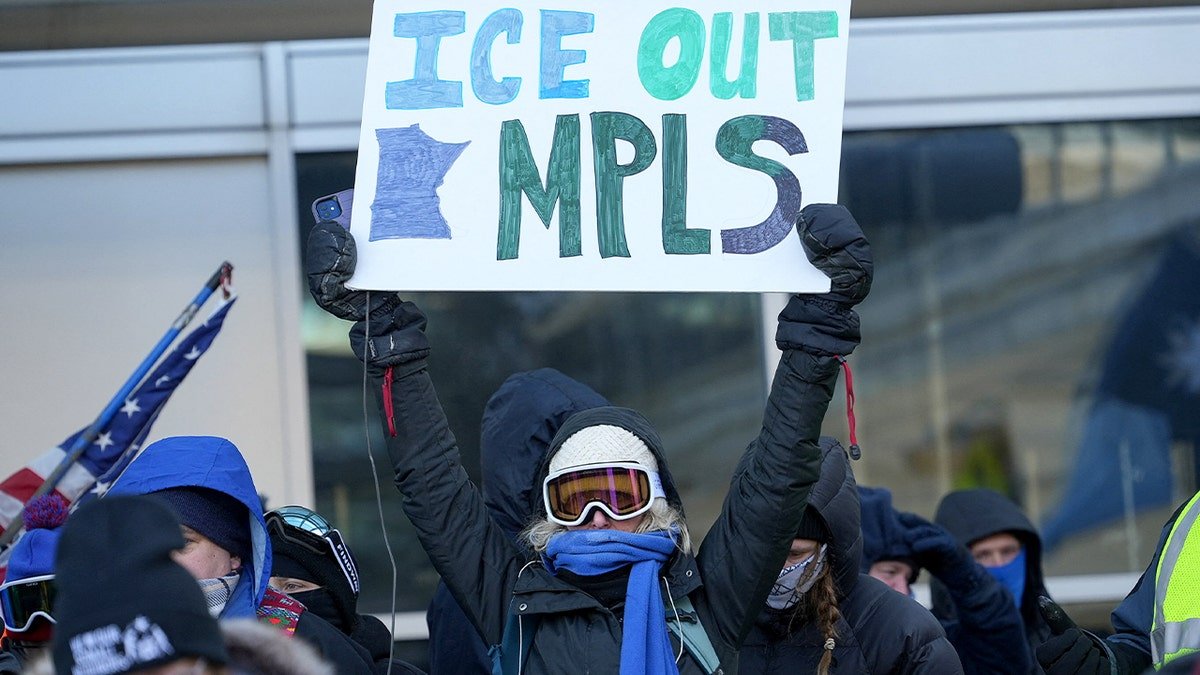 A protester raises a handmade sign opposing immigration enforcement during a street demonstration.