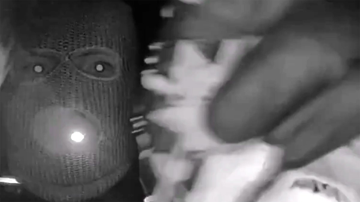 A view from a doorbell camera showing an armed individual outside the residence of Nancy Guthrie in Tucson, Arizona