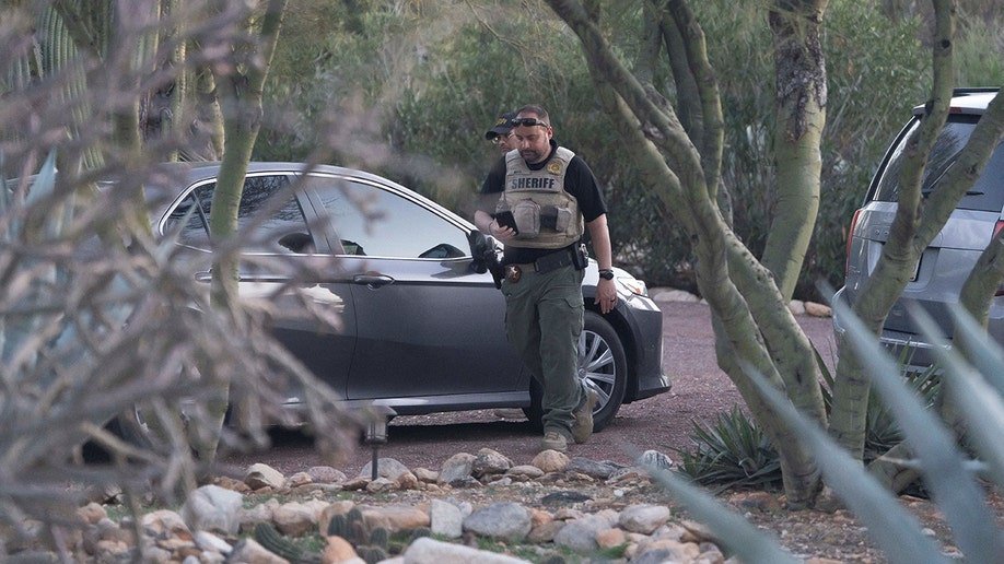 Pima County Sheriff’s deputies walking through Nancy Guthrie's driveway past a parked vehicle.