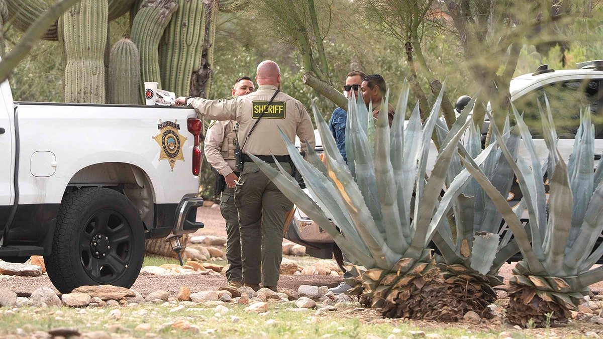 Pima County Sheriff’s deputies standing and talking outside of Nancy Guthrie's home in the Catalina Foothills.