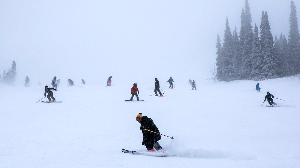 Skiers and snowboarders ride down a snow-covered slope at Jackson Hole Mountain Resort.