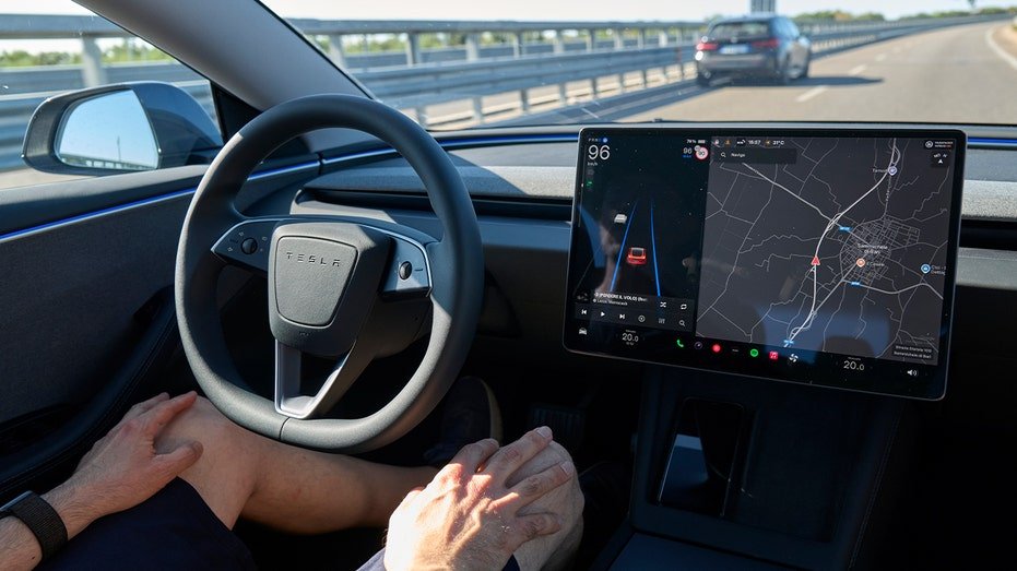 man sitting in tesla driver's seat with hands on thighs