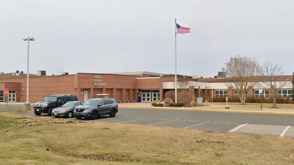 Exterior of Wall High School with an American flag and parking lot.