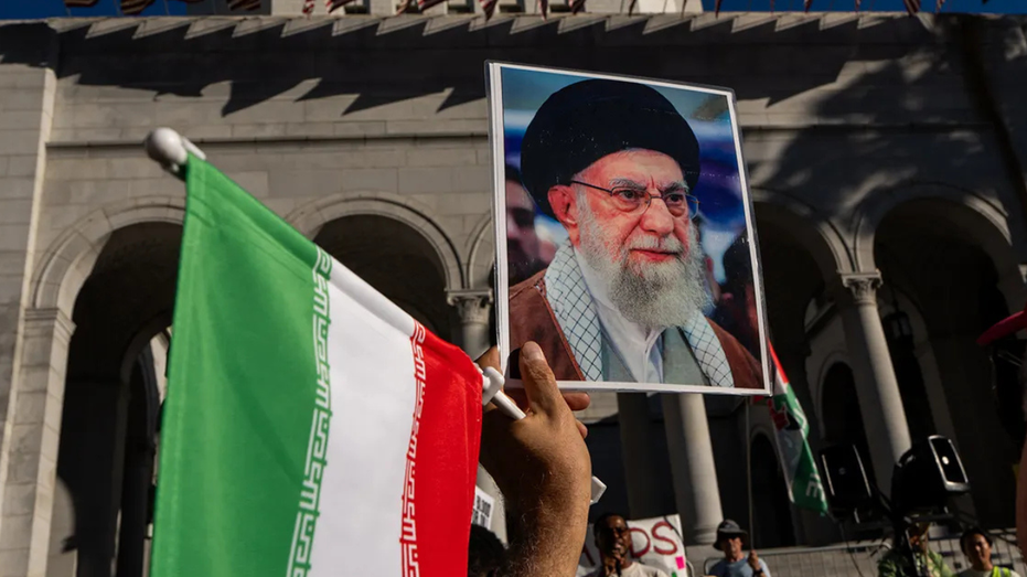 Demonstrator holding Iranian flag and photo of Ayatollah Ali Khamenei