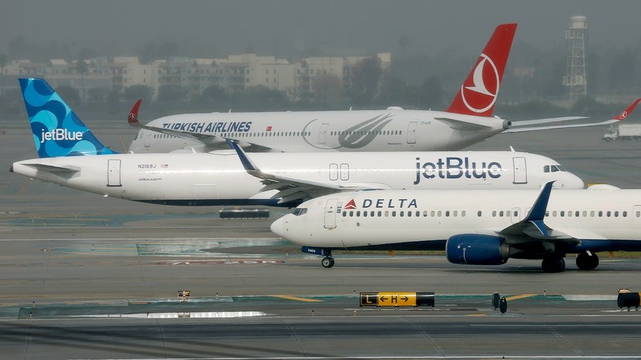Three commercial passenger airplanes from different international carriers move along a runway at a major U.S. airport.