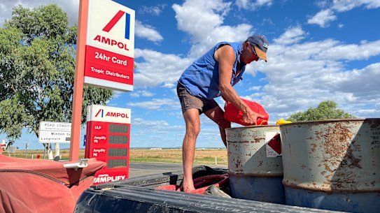 A farmer in Queensland tops up fuel barrels.