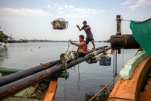 Fishermen in Thailand do maintenance work in the docks while their boats sit idle without fuel. 