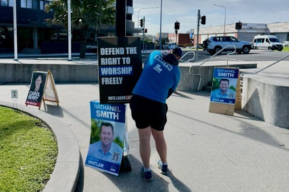 A Brethren member in a Liberal Party T-shirt puts up a poster during the last federal election campaign.