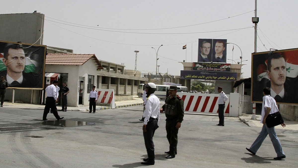 Syrian police officers stand guard at the entrance of Damascus Central Prison in the Adra area.