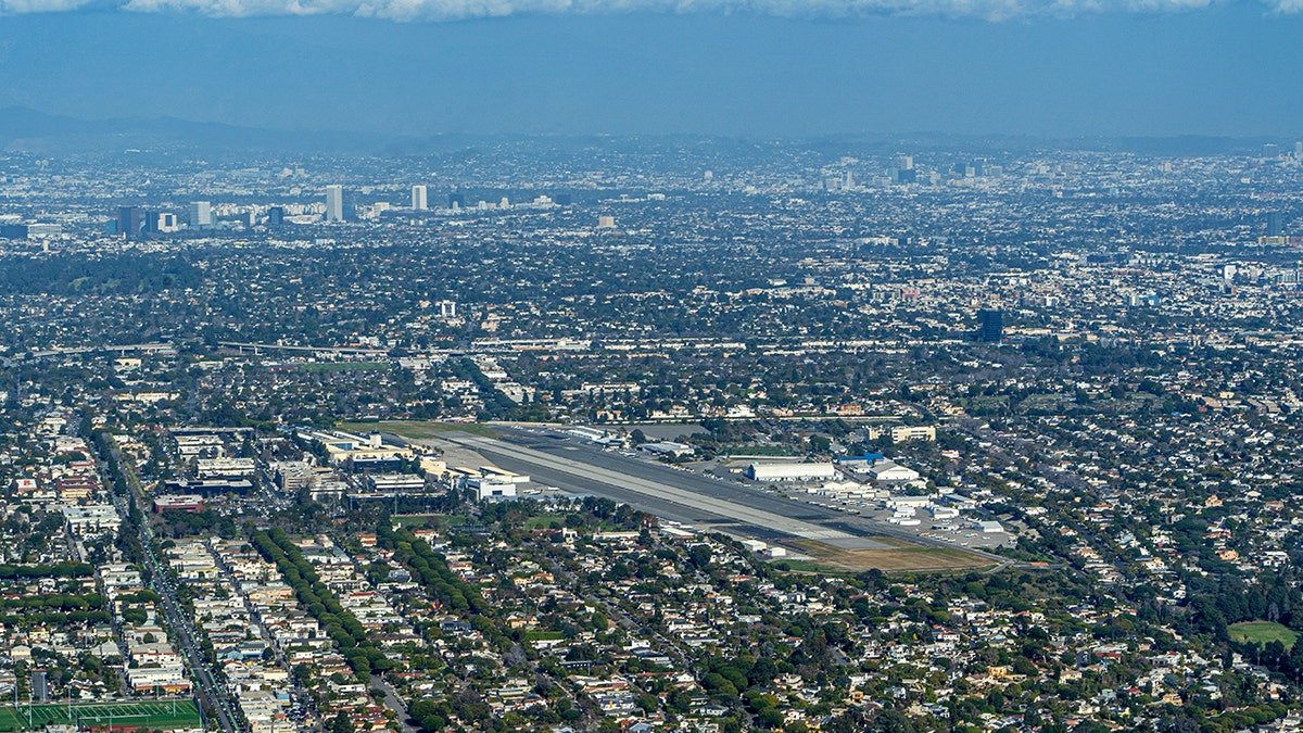 Aerial view of a city with an airport runway and housing.