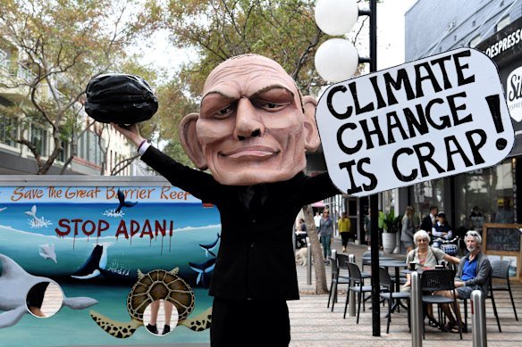 A protester wears a Tony Abbott head holding what looks like a piece of coal.