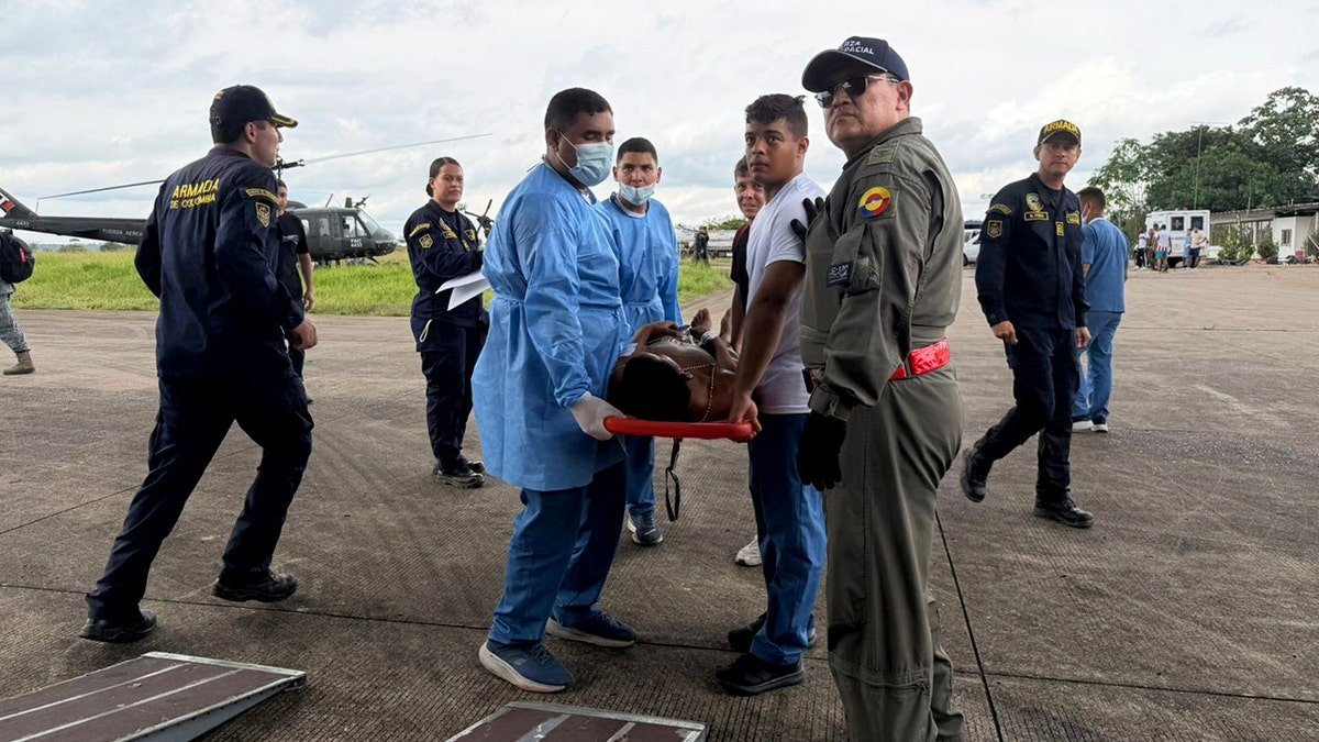 People prepare to load an injured person on a stretcher into a plane.