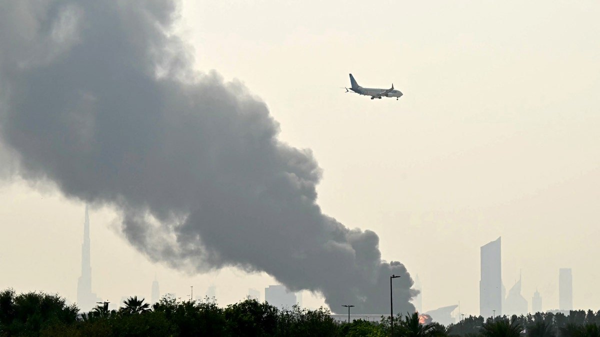 airplane flying over city with smoke in dubai