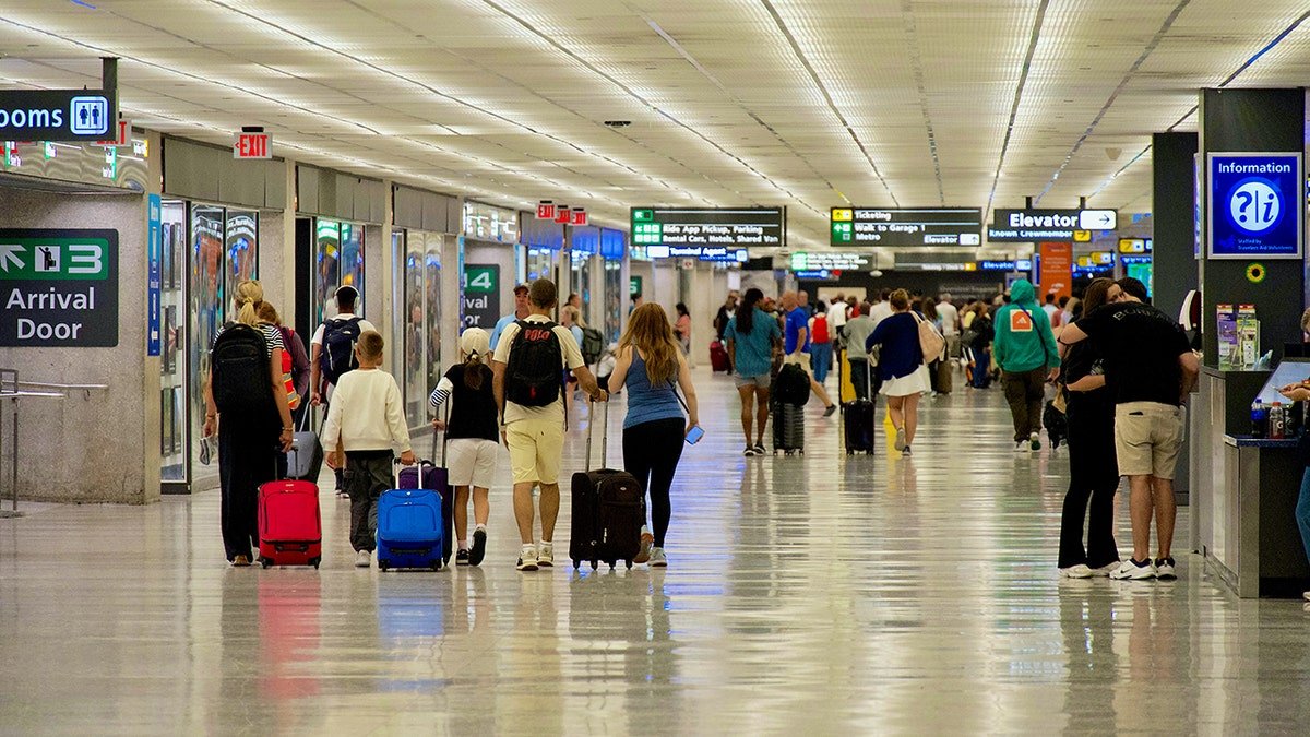 Travelers walking through Dulles airport terminal with suitcases.