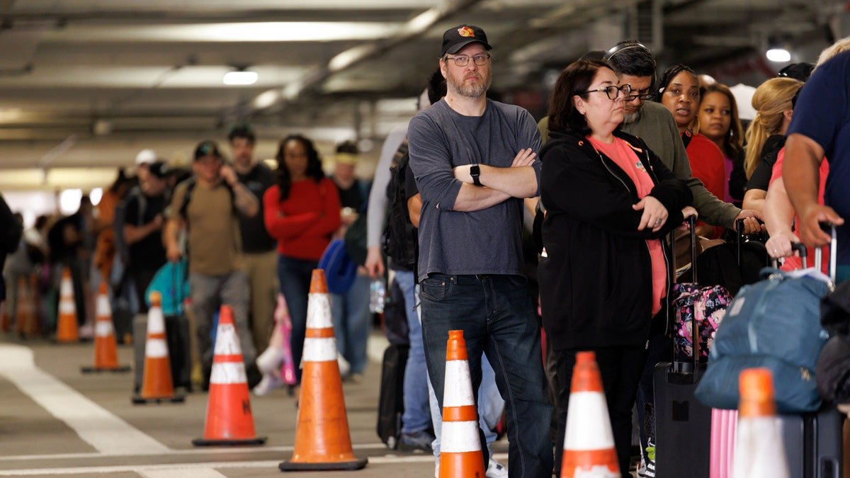 Flight passengers wait in TSA line in parking lot at Houston Airport.
