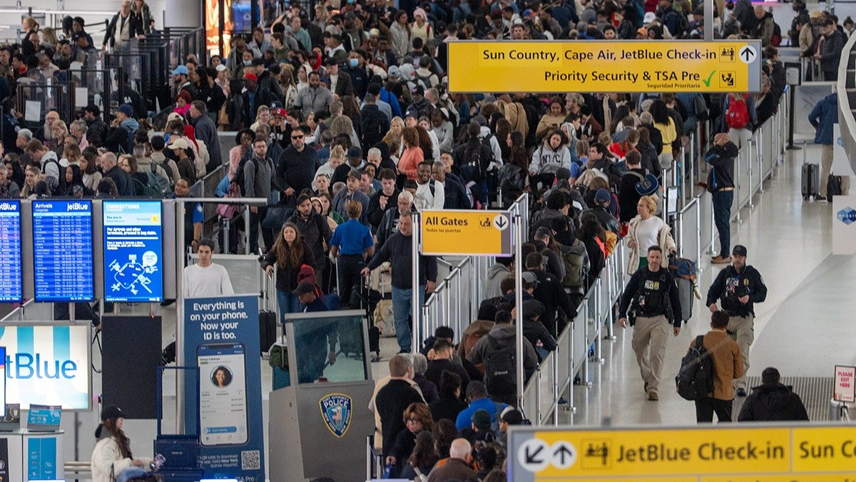 Passengers standing in a long queue at a JFK Airport security checkpoint.