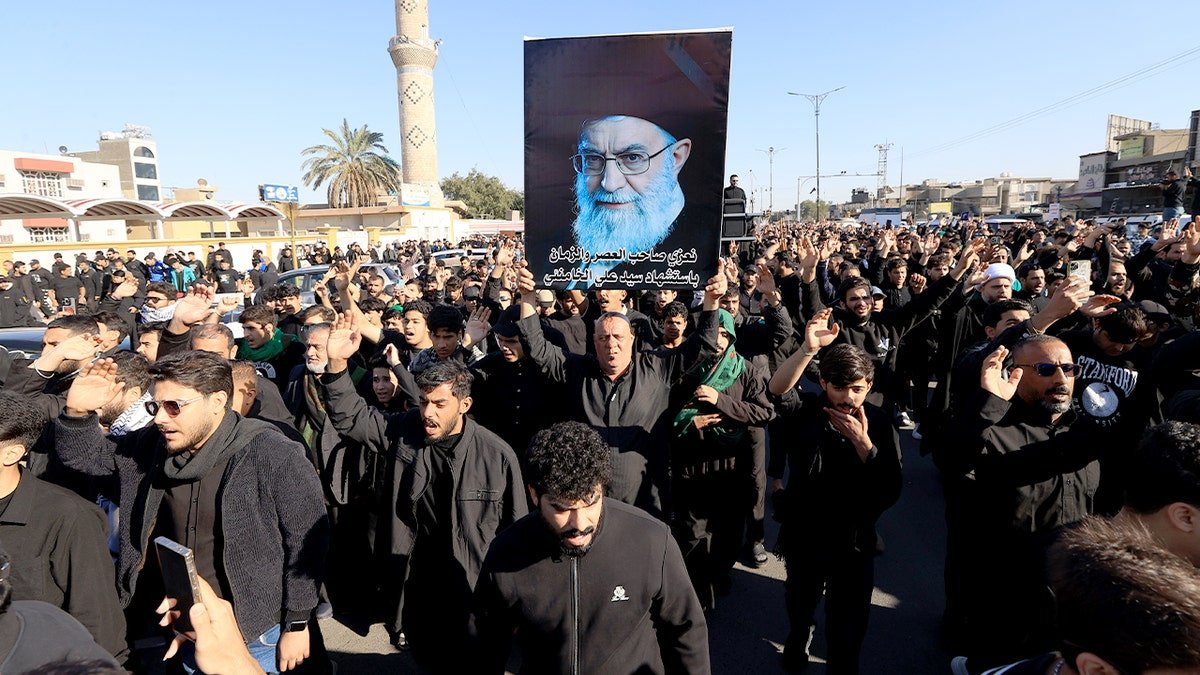Demonstrators in Baghdad’s Sadr district wave Iranian flags and hold portraits of Iran’s supreme leader during a street protest.