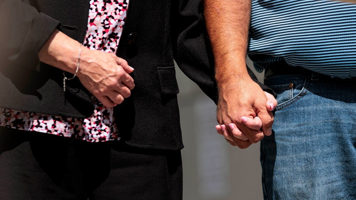 North Andover police officer Kelsey Fitzsimmons' mother and stepfather hold hands