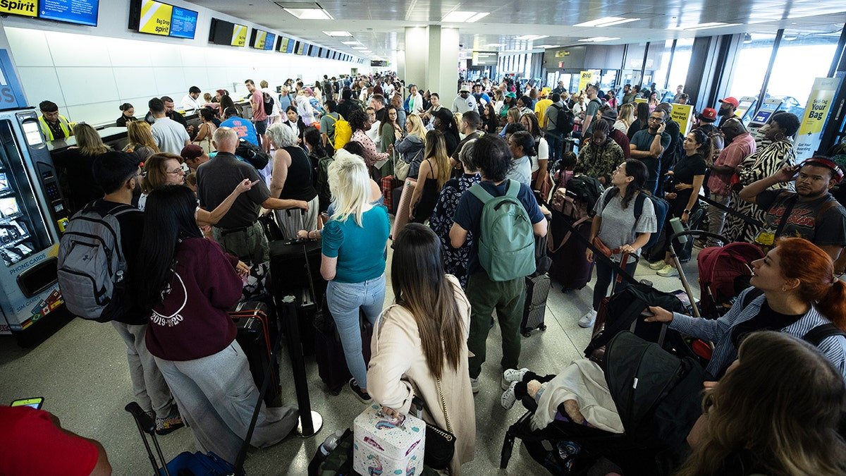 A group of people are waiting in the area to check their bag at the airport. People look stressed, tired and overwhelmed.