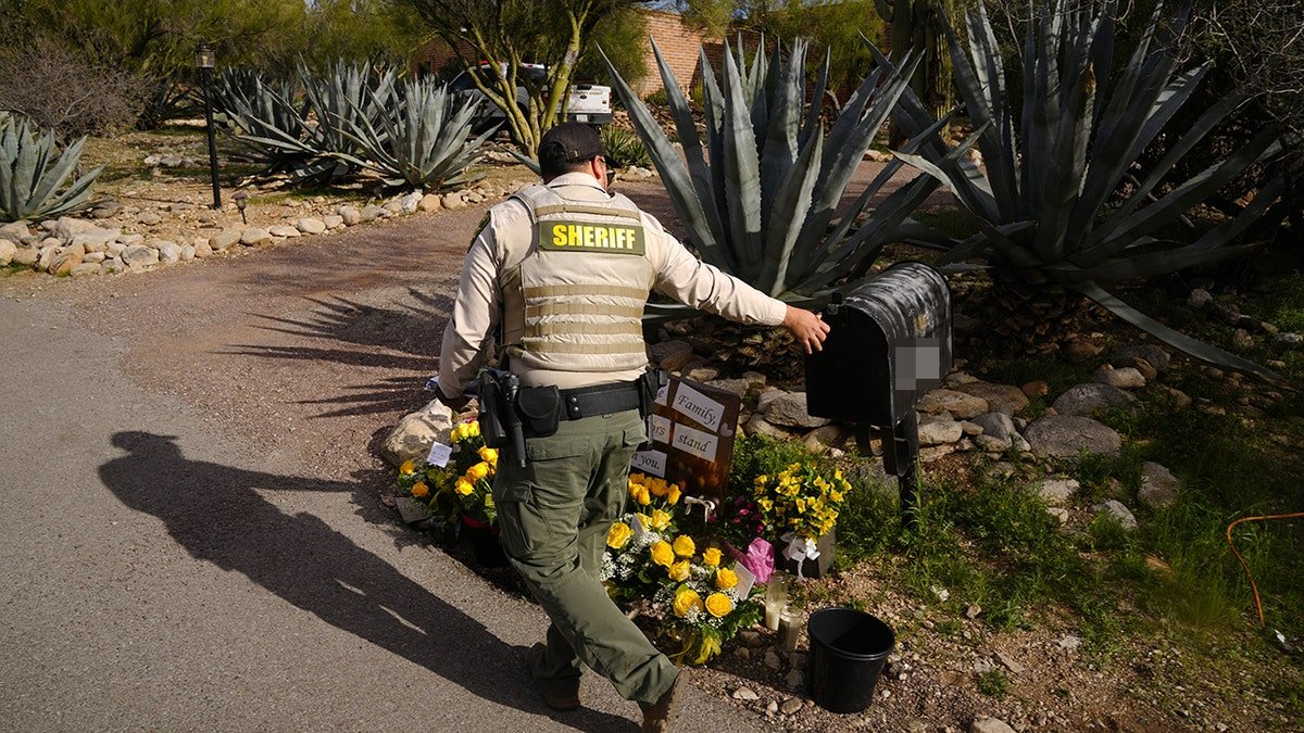 A Pima County Sheriff's deputy reaching into a mailbox to retrieve mail at Nancy Guthrie's home.